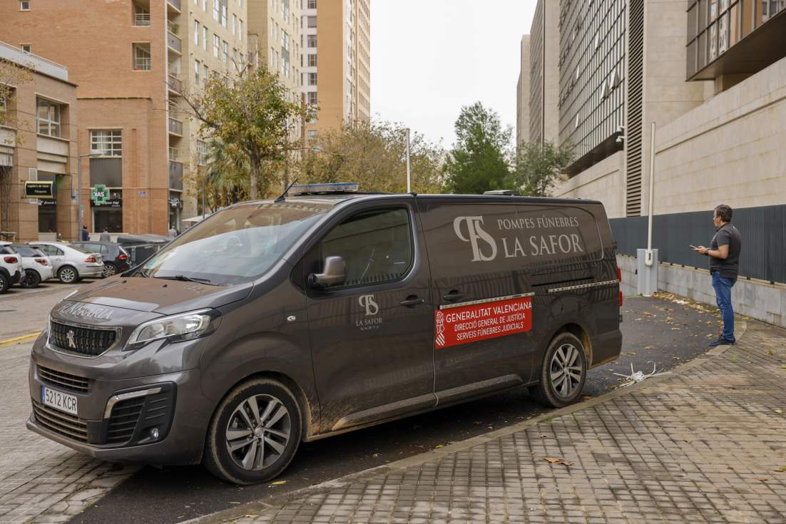 Una persona aguarda junto al vehículo del retén fúnebre estacionado en la Ciudad de la Justicia donde se encuentra el instituto de medicina legal. EFE/Ana Escobar