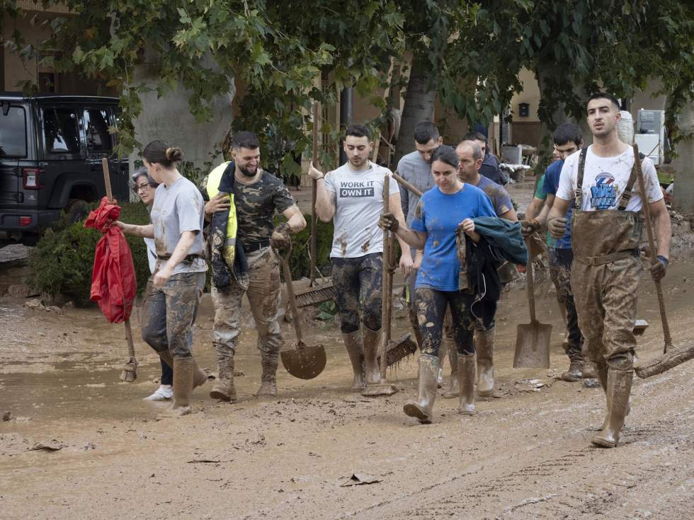 Varias personas colaboran en la limpieza de una calle afectada. EFE/Álvaro del Olmo
